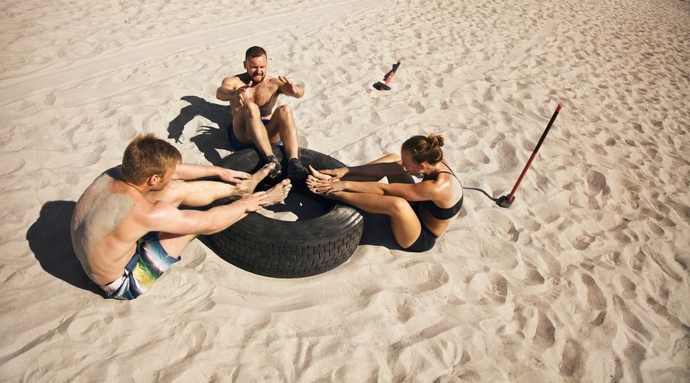 colegi de echipa implicati intr-un joc pe plaja cu un cauciuc